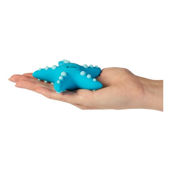 Türkisfarbener Auflegevibrator in Seesternform, auf einer Handfläche liegend. Knöpfe und Ein-/Ausschalter.