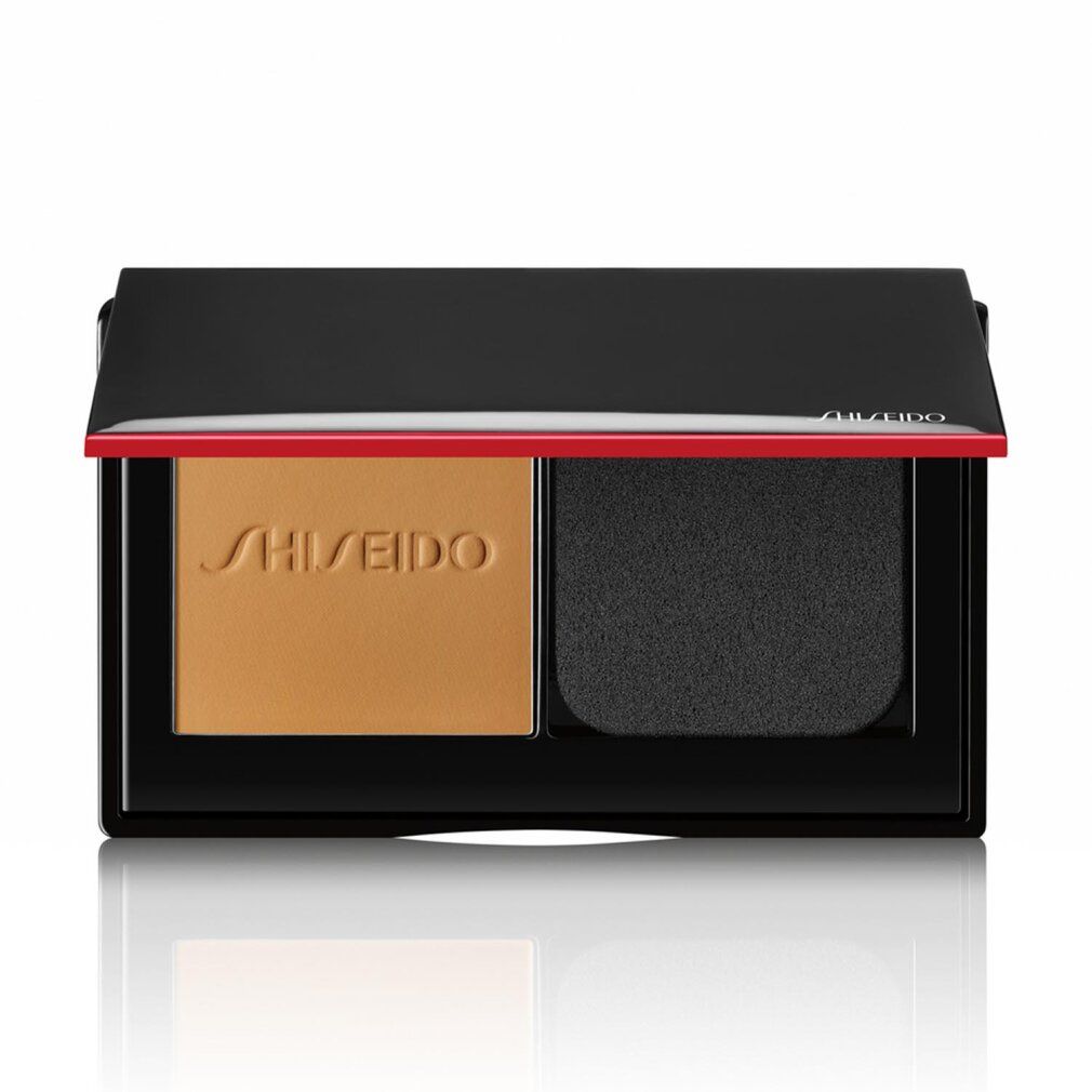 Kompakt-Puder-Foundation. Schwarzes Gehäuse mit roter Linie und Schriftzug SHISEIDO. Hellbraunes Puder und Schwamm.
