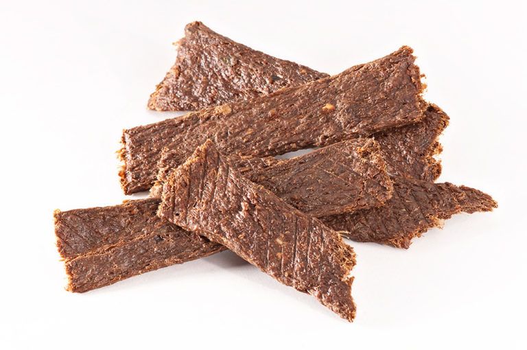 Mehrere Streifen Trockenfleisch, braun, auf weißem Hintergrund. Die Textur ist deutlich sichtbar.