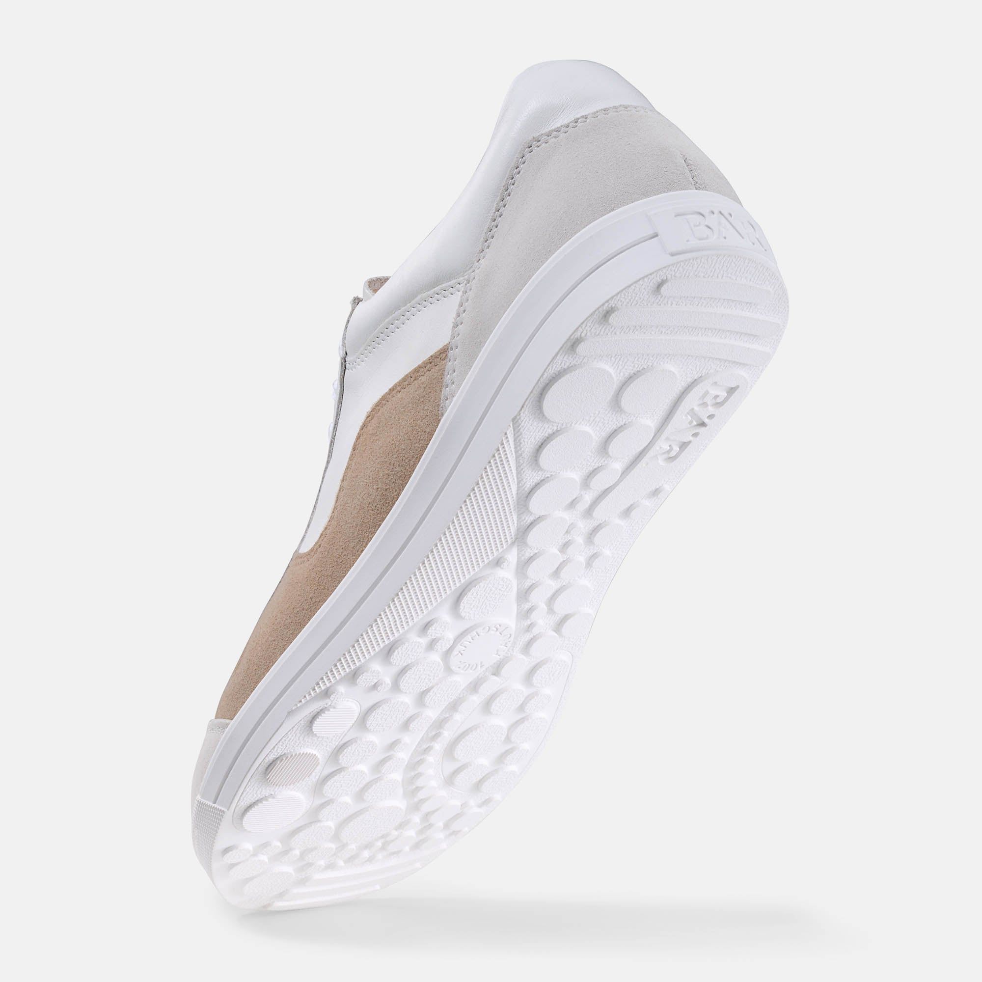 Weiße Schuhsohle mit Noppenmuster. Beige und weißes Obermaterial. Blick von unten.