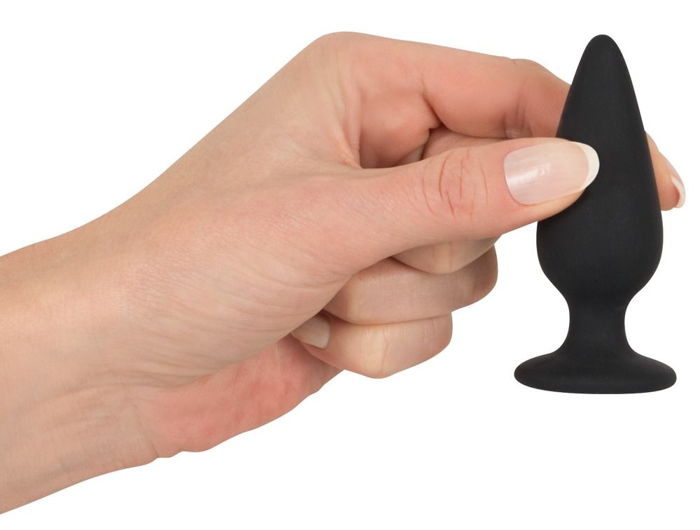 Hand hält schwarzen Analplug. Konische Form, breiter Standfuß. Hautfarbe.