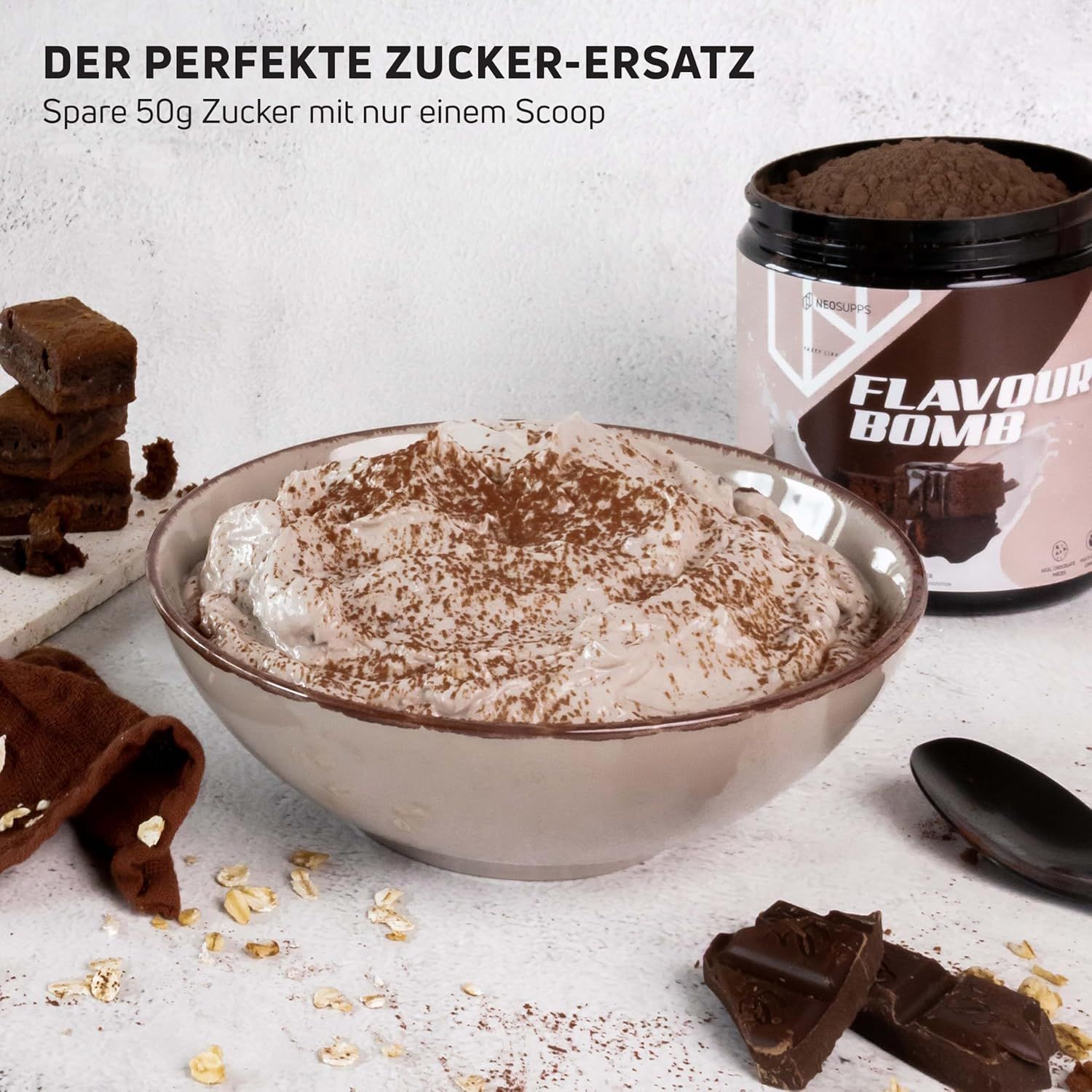 Schüssel mit Creme, bestreut mit Kakaopulver, neben Dose FLAVOUR BOMB und Brownies. Text: Der perfekte Zucker-Ersatz. Spare 50g Zucker mit nur einem Scoop.