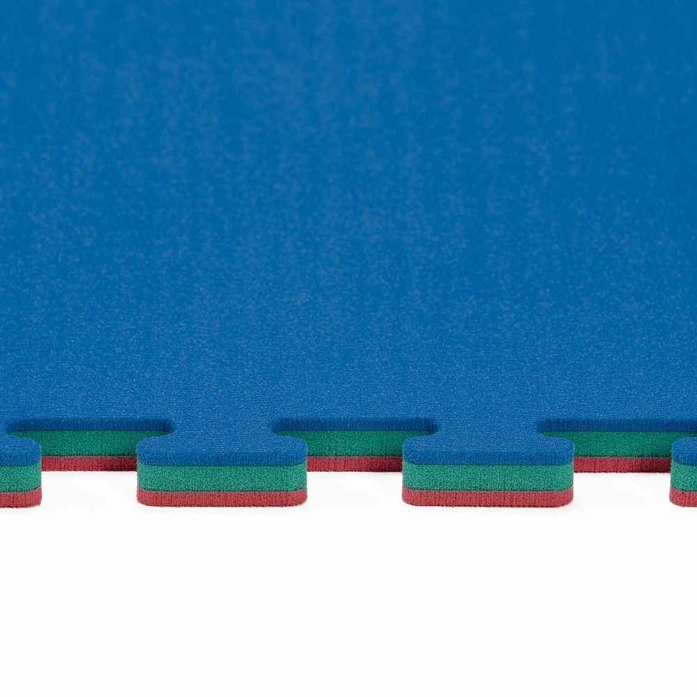Blaue Fitnessmatte mit ineinandergreifenden Kanten. Grün und rotfarbige Schichten sind an den Kanten sichtbar.