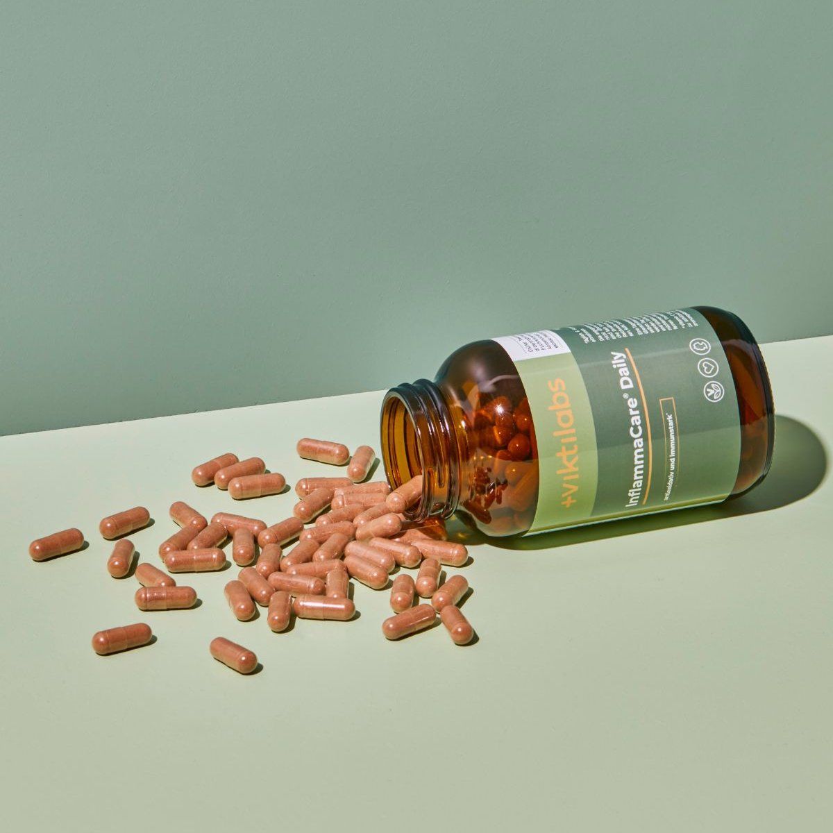Braune Glasflasche liegt umgekippt, Kapseln verteilen sich. Aufschrift: Viktilabs InflammaCare® Daily.