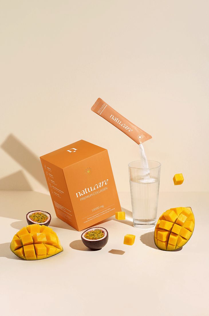 Pulver wird in Glas gegossen. Schachtel, Mango, Maracuja. Aufschrift "natu.care".