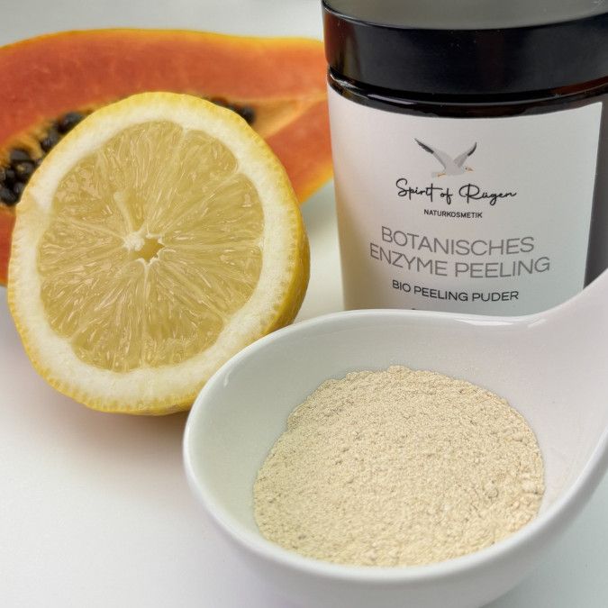 Glasdose, Zitrone, Papaya und Pulver in Schale. Dose mit Etikett, Produktname. Zitrone halbiert, Papaya geschnitten.