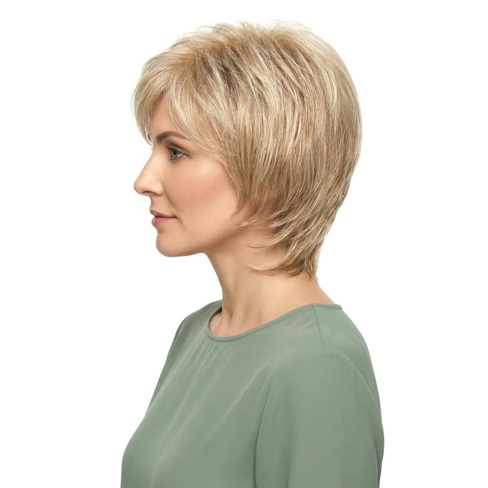 Kurzhaarperücke, blond-braun meliert, mit Pony. Frau trägt ein grünes Oberteil. Seitenansicht.