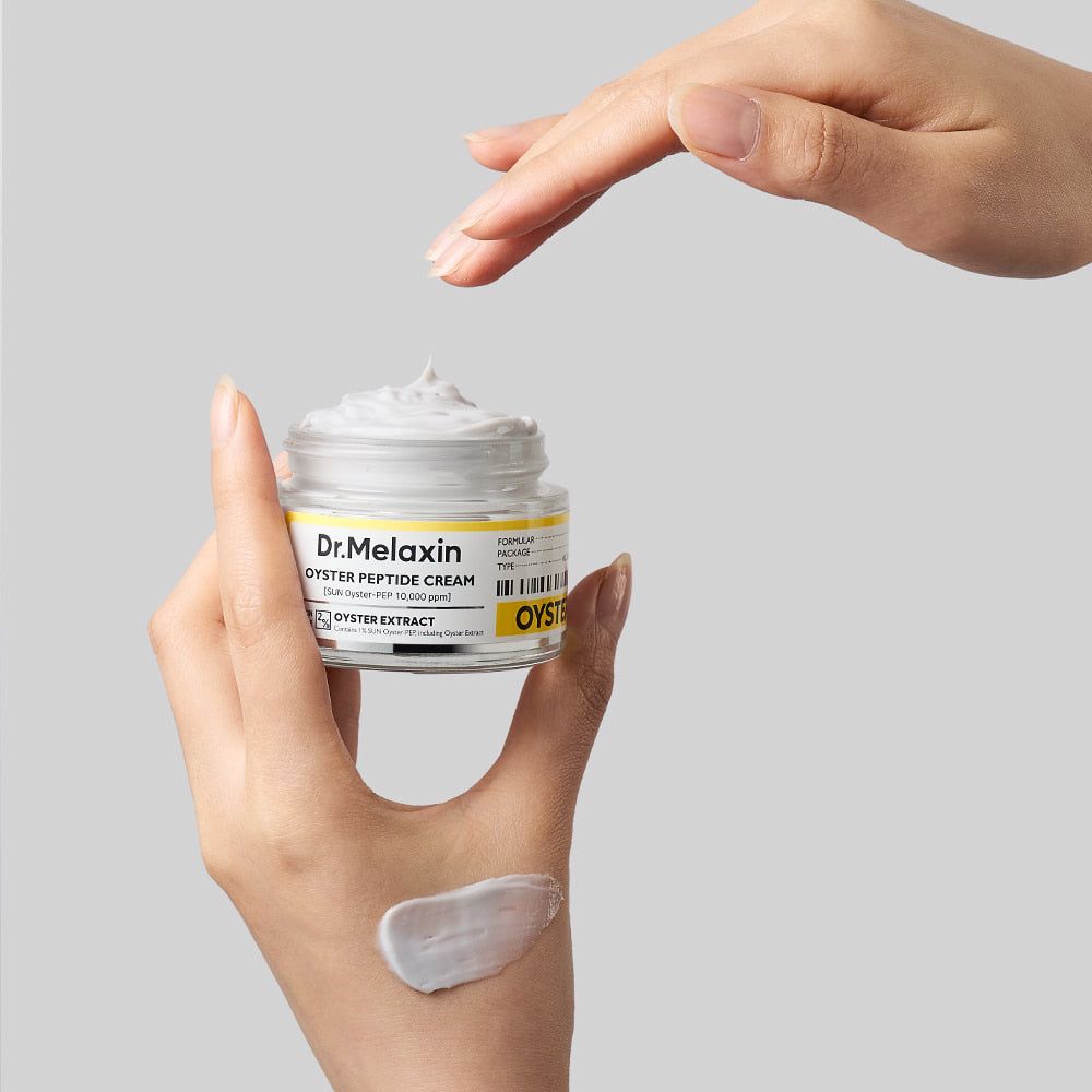 Hand hält Dr. Melaxin Oyster Peptide Cream, mit Cremeprobe auf der Handfläche.