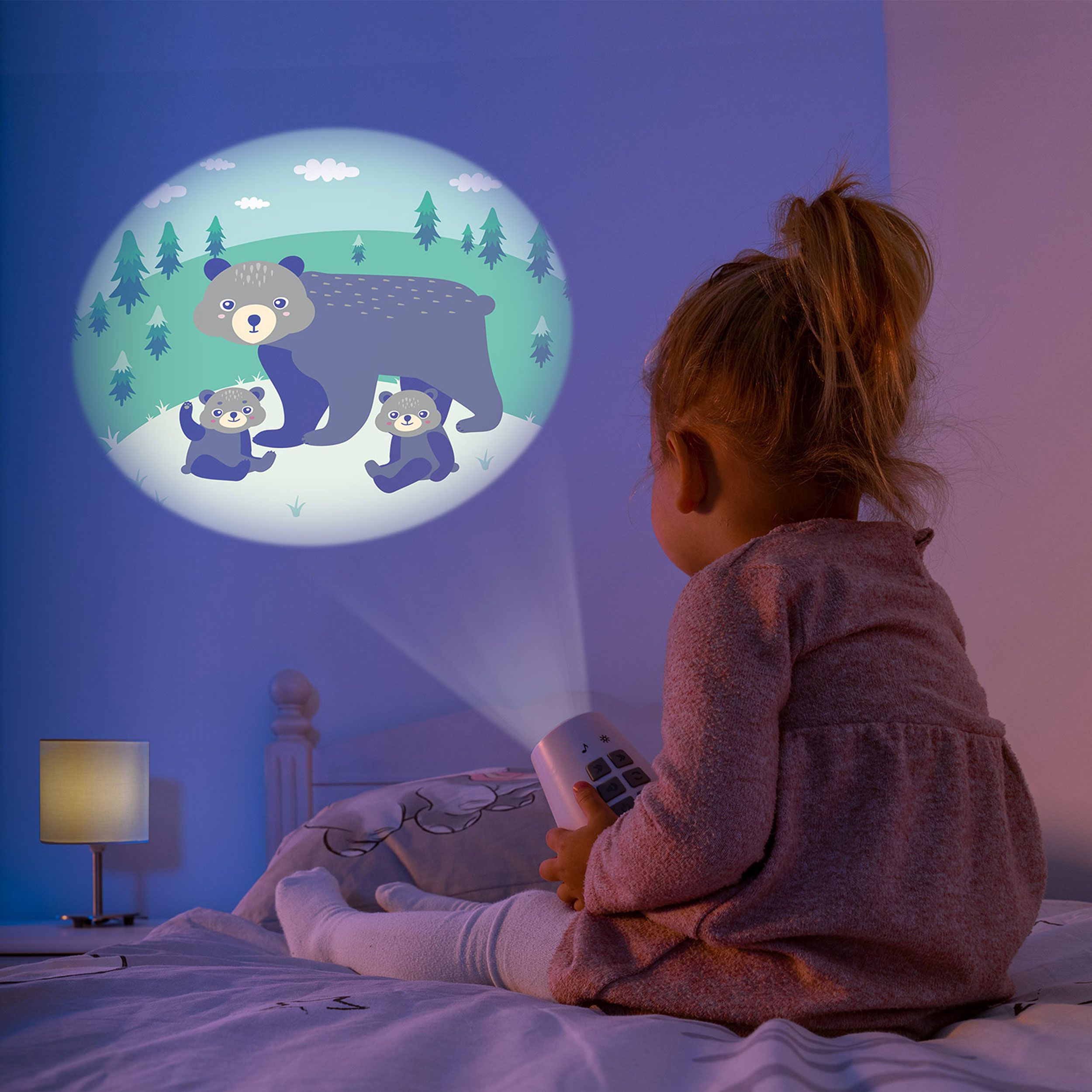 Projektor mit Bärenmotiv an Wand. Kind sitzt davor mit Fernbedienung. Projektor mit LEDs.