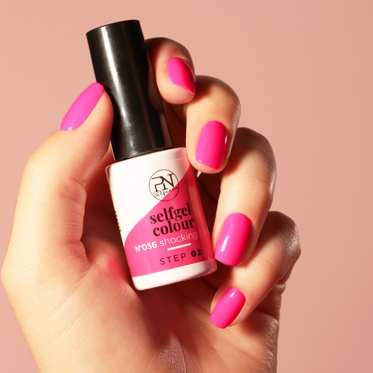 Hand hält eine Nagellackflasche und zeigt lackierte Nägel. Die Flasche trägt die Aufschrift "selfgel colour".