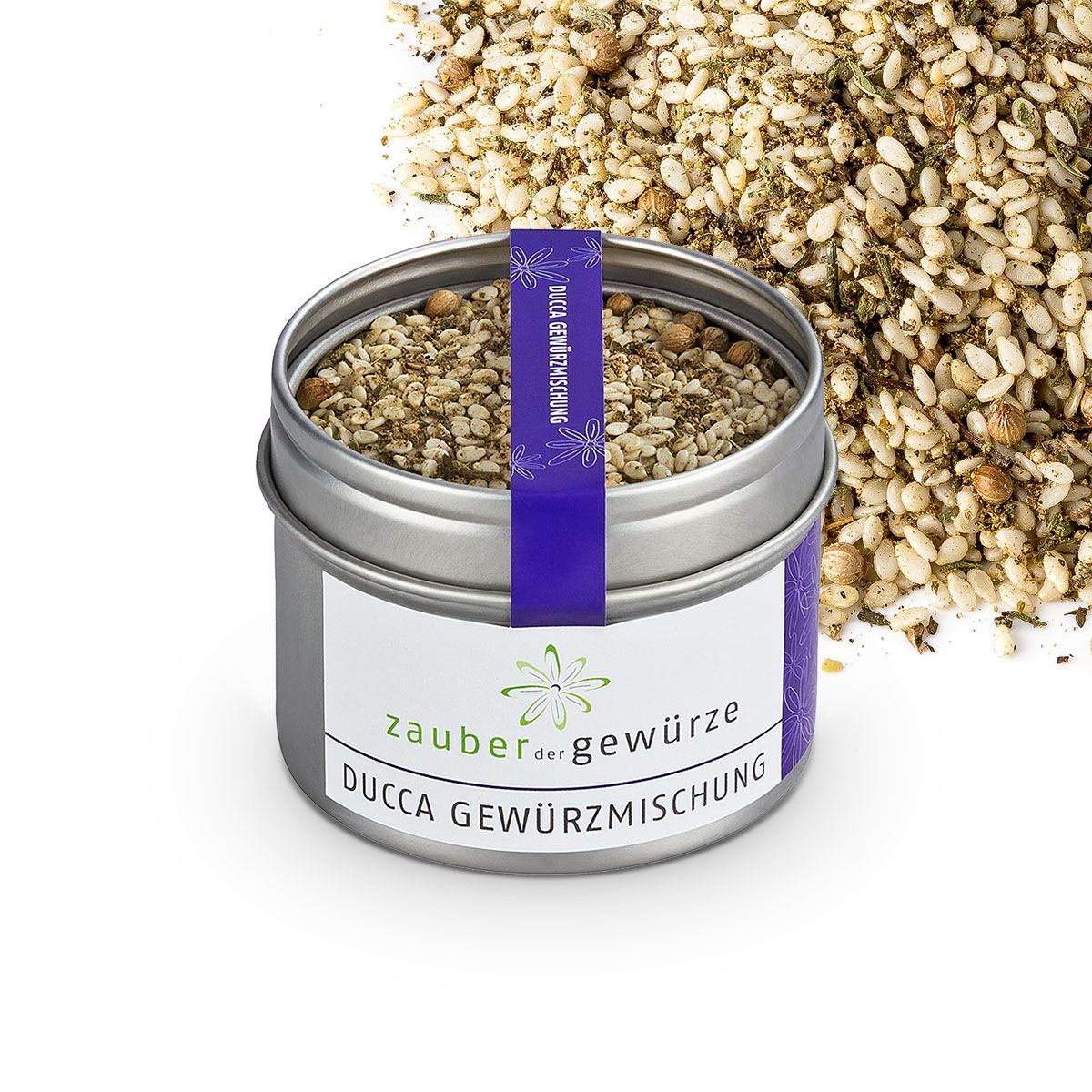 Geöffnete Dose Ducca Gewürzmischung. Blaue Banderole mit Text. Weißes Etikett mit Logo und Schriftzug: Zauber der Gewürze Ducca Gewürzmischung. Gewürze verstreut.