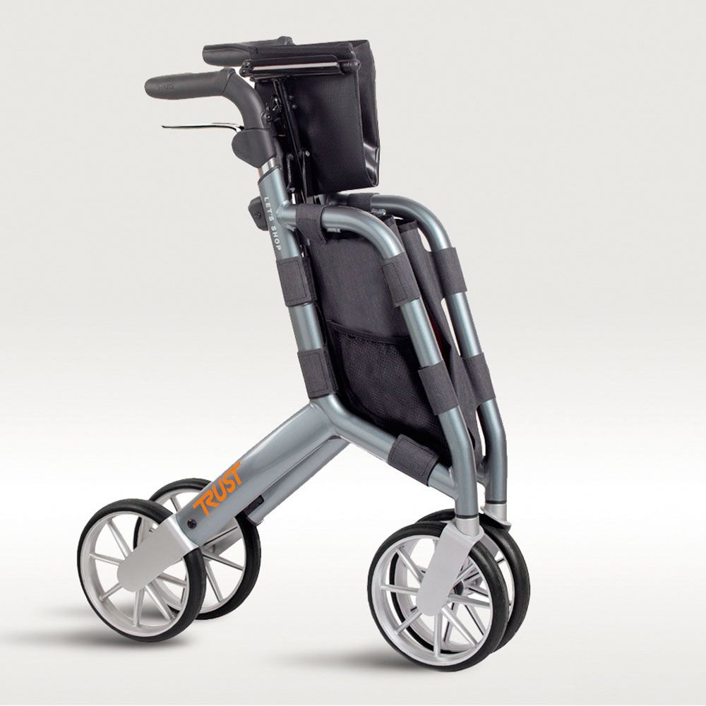 Zusammengeklappter Rollator mit grauem Rahmen, schwarzer Tasche und vier Rädern. Auf dem Rahmen steht "TRUST".
