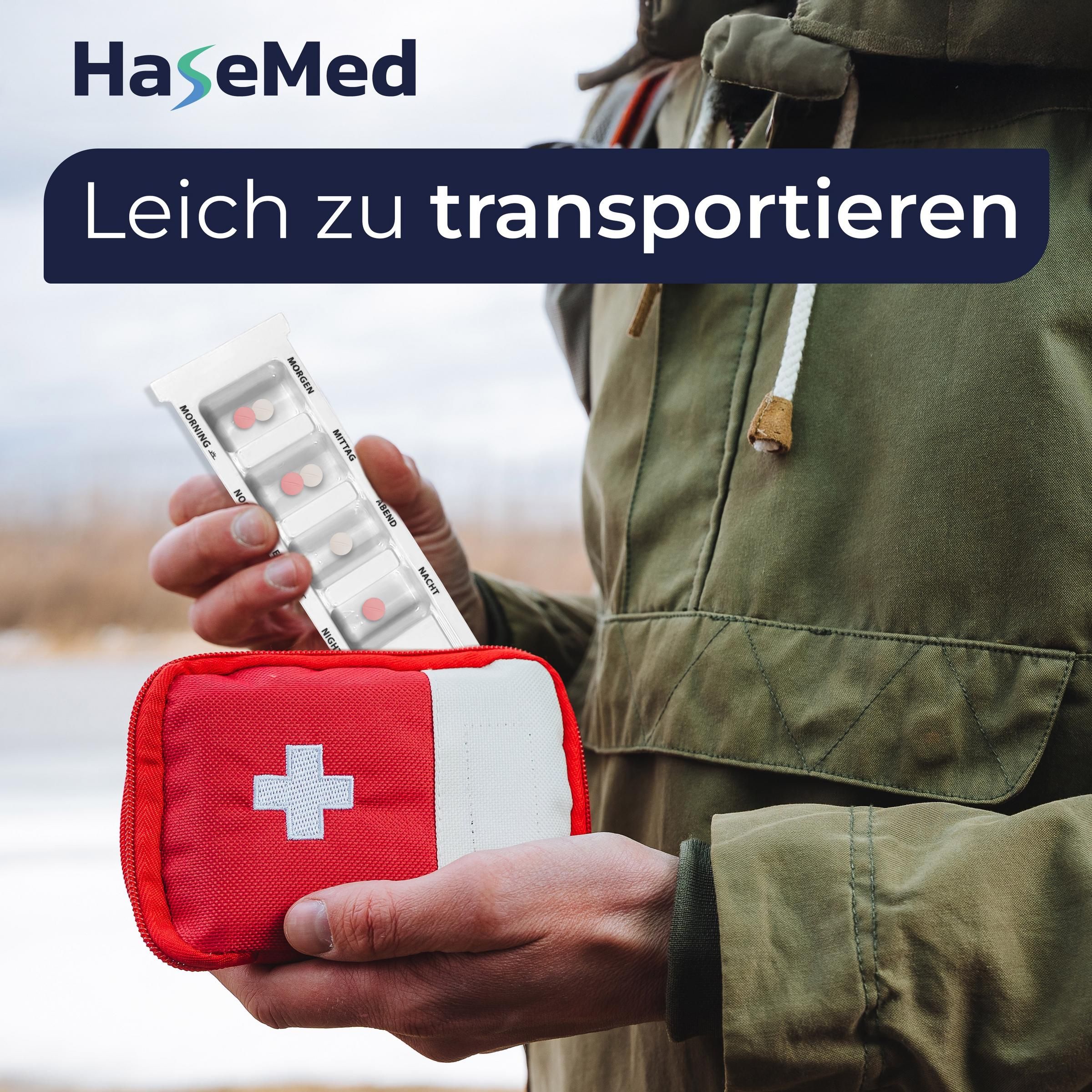 Person hält Medikamentendispenser und rotes Erste-Hilfe-Set. Medikamentendispenser mit Tabletten. Marke HaseMed. Hintergrund: Natur.