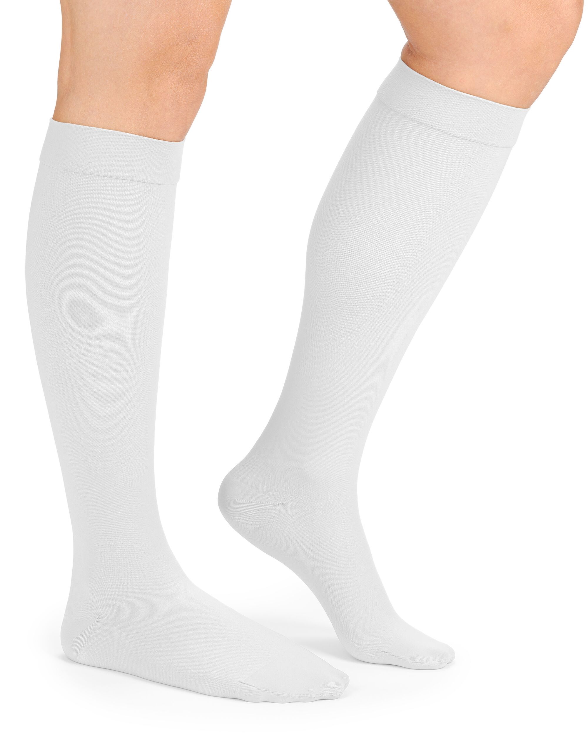 Weiße Kompressions-Kniestrümpfe an Beinen. Die Strümpfe reichen bis unterhalb des Knies. Der obere Rand ist umgeschlagen.