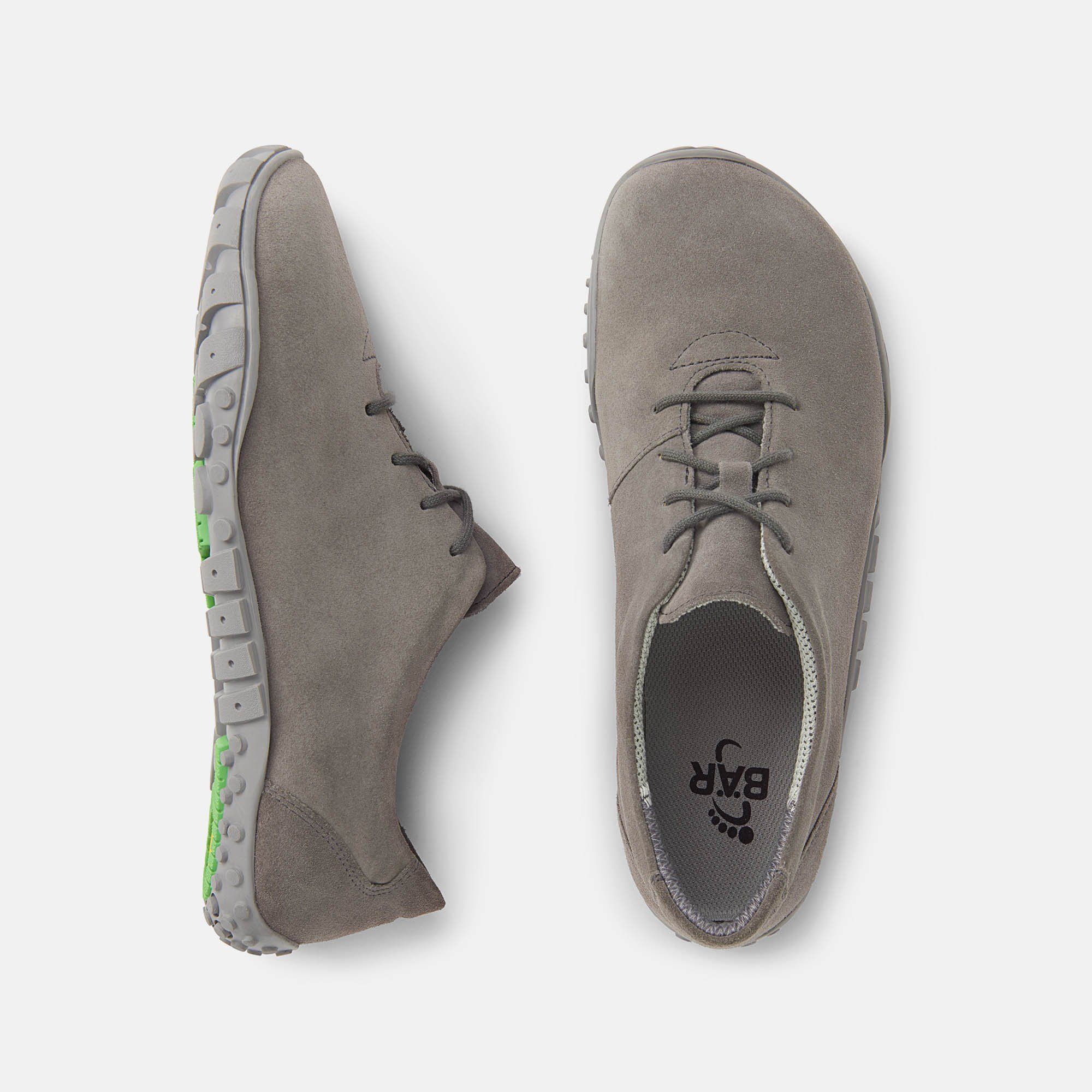 Graue Schnürschuhe. Breiter Schnitt. Sohle mit Profil. Draufsicht auf zwei Schuhe. Grüne Akzente an der Sohle.