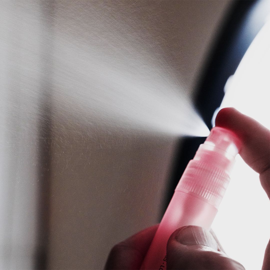 Hand spuit roze vloeistof uit een roze spray. De achtergrond is wazig.