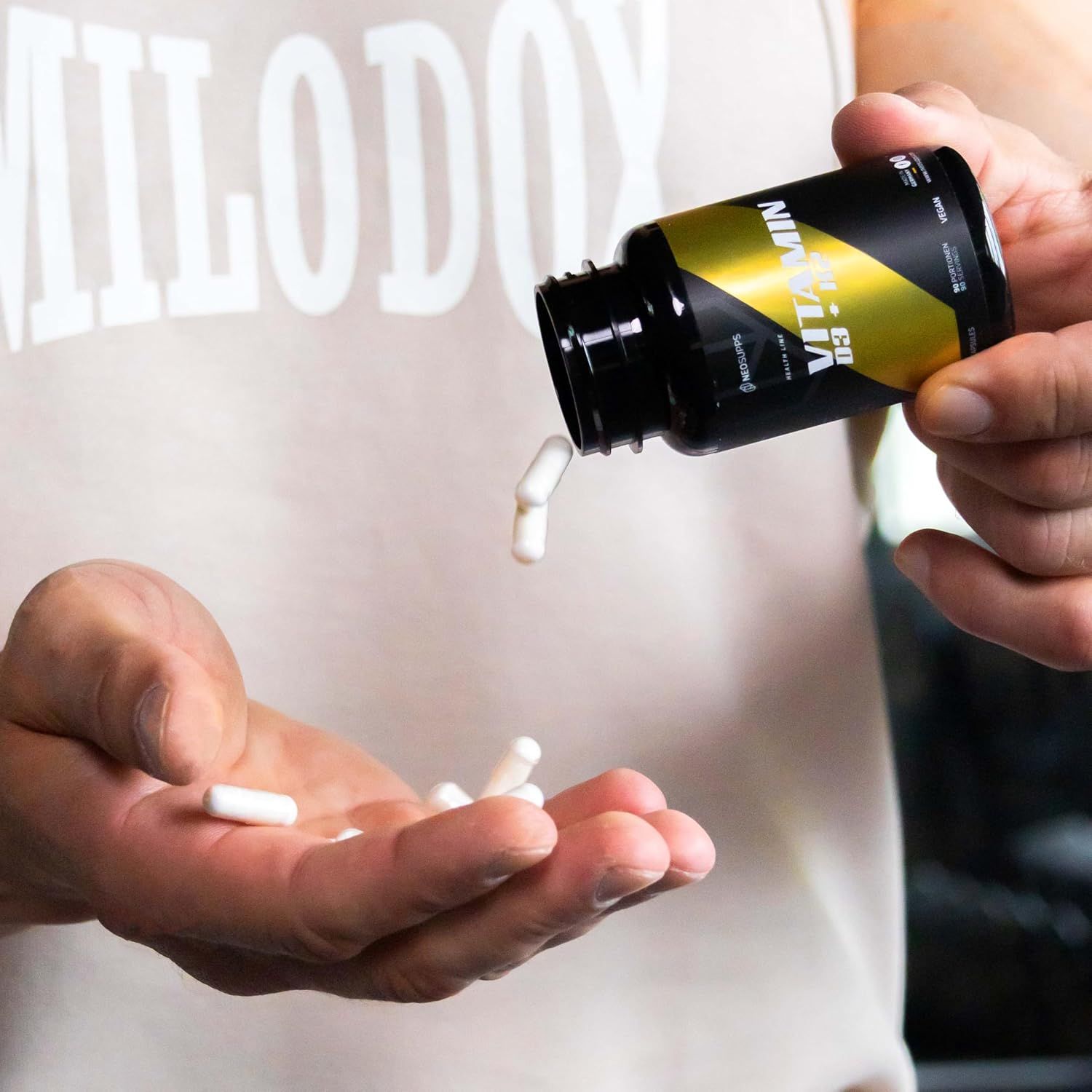 Mann hält eine Flasche und Kapseln in der Hand. Auf der Flasche steht Vitamin D3 + K2.