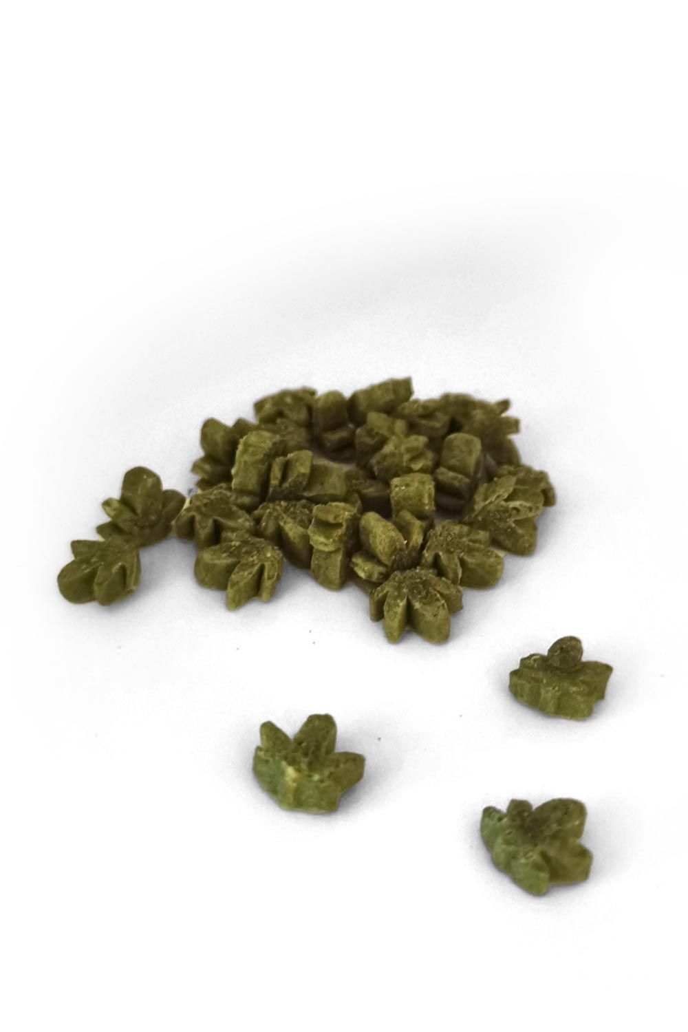 Haufen grüner, blattförmiger Snacks. Einzelne Snacks liegen verstreut. Auf weißem Hintergrund.