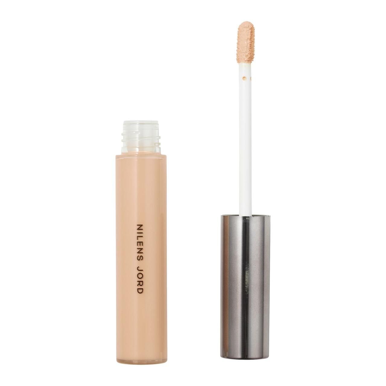 Beige Concealer-Tube mit geöffnetem Deckel und Applikator. Aufschrift: NILENS JORD. Applikator mit Produkt.
