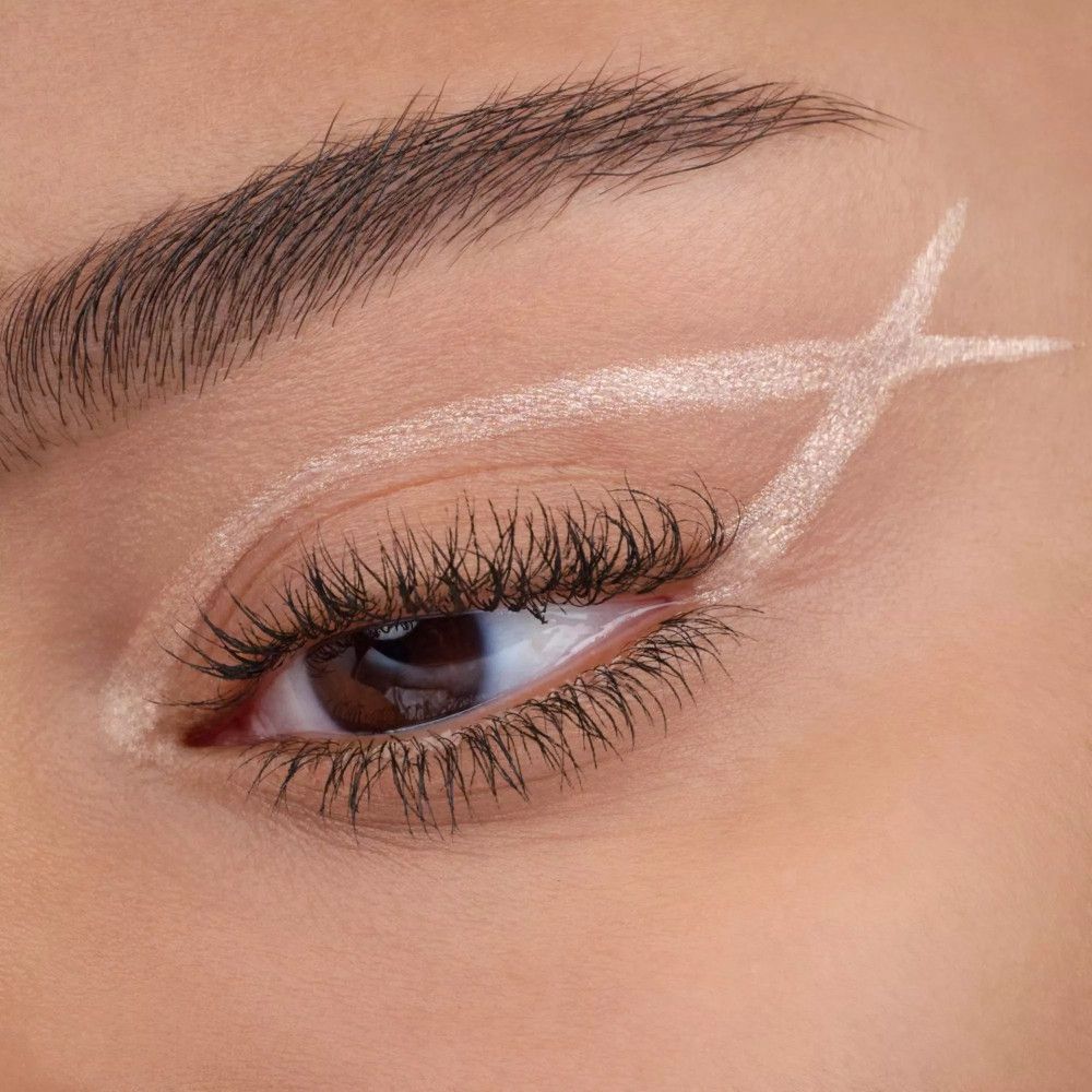 Nahaufnahme eines Auges mit hellem Eyeliner. Der Eyeliner ist in einer X-Form aufgetragen.