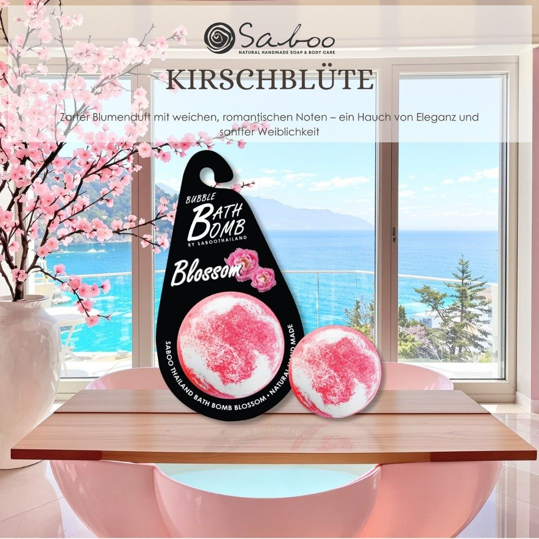 Zwei Schaumbad-Bomben. Text: Kirschblüte. Zarter Blütenduft. Auf einem Tisch vor Fenster und Meer.