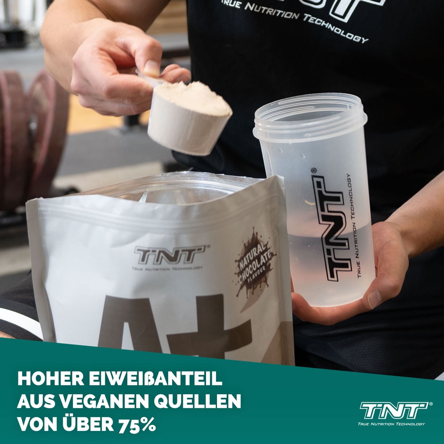 Person gibt TNT A+ Protein Pulver in einen Shaker. Aufschrift auf dem Beutel: A+ Protein, Natural Chocolate Flavour. Shaker mit Wasser.