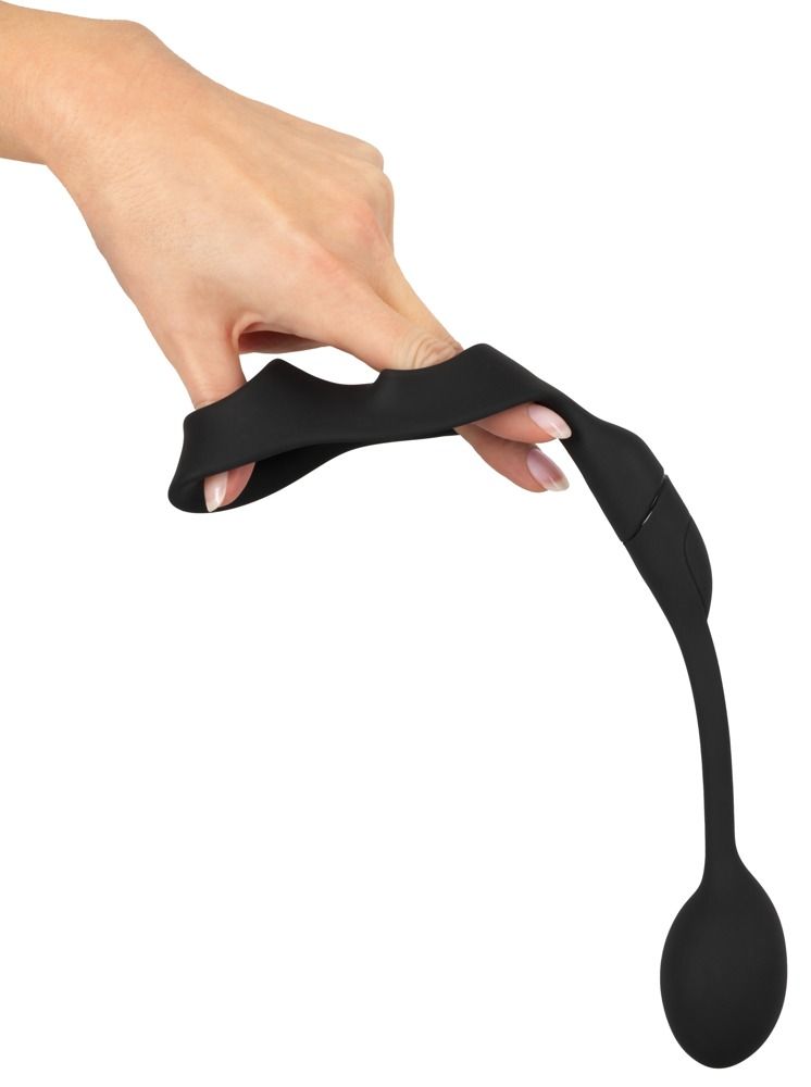Hand hält und biegt schwarzen Penisring mit Hodenring und Analplug. Flexibles Material.