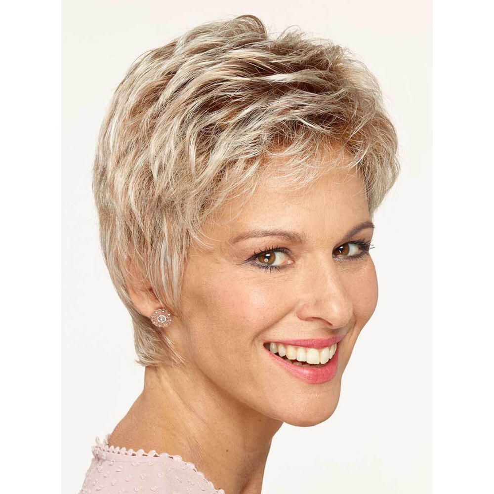 Kurzhaarperücke in Blondtönen. Frau mit Perücke, lächelnd. Ohrringe. Rosa Oberteil. Heller Hintergrund.