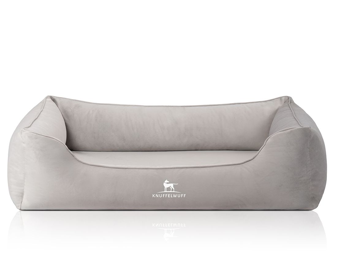 Graues orthopädisches Hundebett mit erhöhtem Rand. Logo unten rechts. Rechteckige Form, weiches Material.