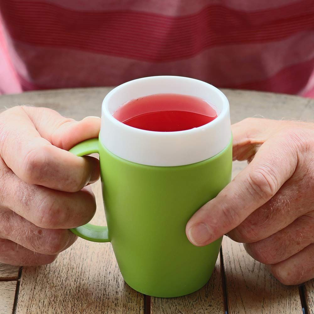 Grüner Becher mit weißem Rand, gefüllt mit roter Flüssigkeit. Hände halten den Becher.