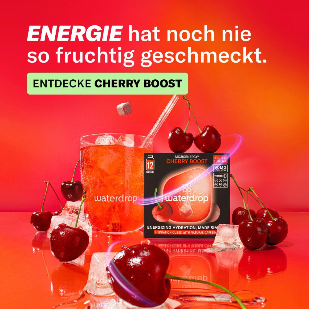 Glas mit Getränk, Kirschen und Produktverpackung. Aufschrift: Microenergy Cherry Boost, 12 Portionen, ohne Zucker, 90mg, Koffein.