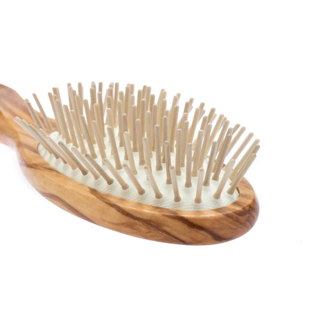 Primo piano di spazzola per capelli ovale in legno d'ulivo con perni in legno.