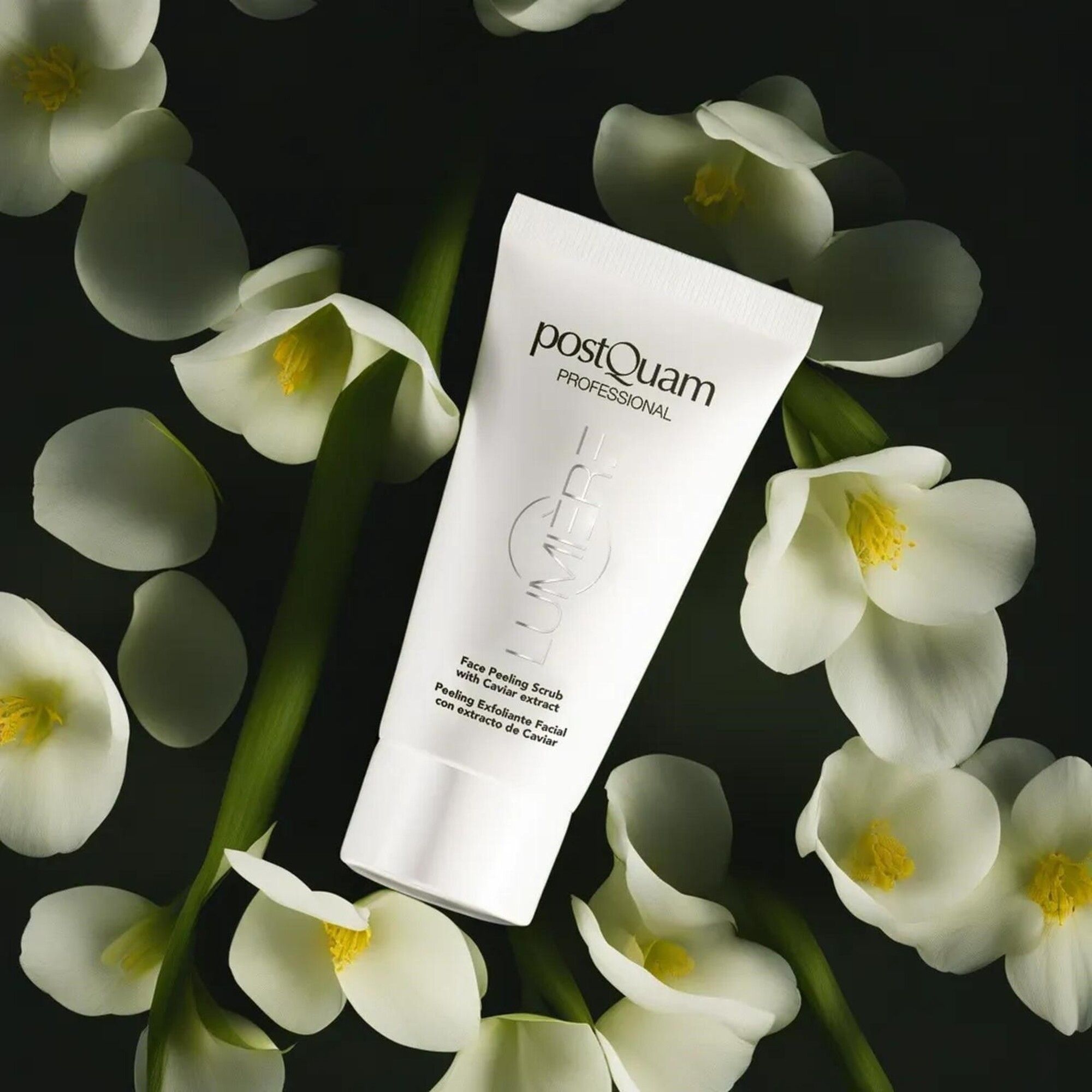 Weiße Tube mit Produktnamen und Text. Umgeben von weißen Blüten auf dunklem Hintergrund. Text: Face Peeling Scrub with Caviar extract.