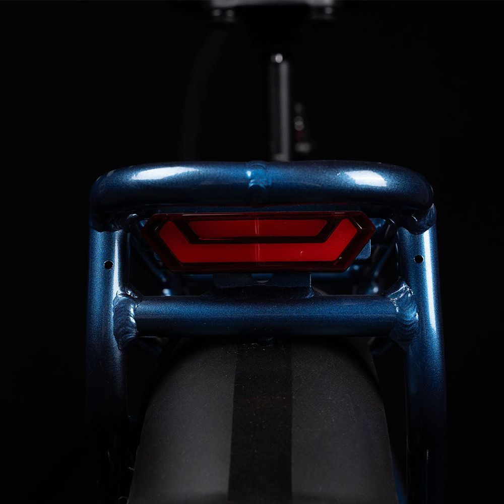 Rückansicht eines blauen E-Bikes. Gepäckträger und rotes Rücklicht. Schwarzer Kotflügel.