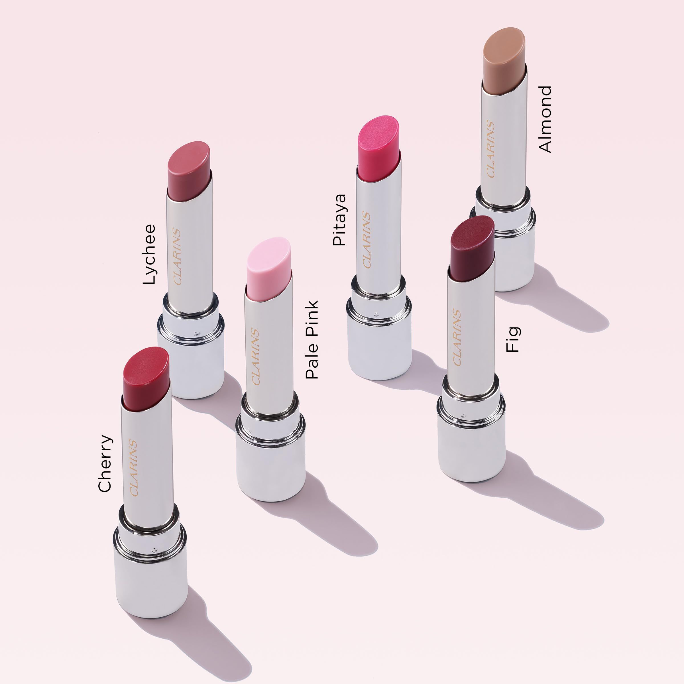 Sieben Lip Oil Balm Lippenstifte. Verschiedene Farben. Weißer Körper, goldfarbener Boden. Aufschrift.