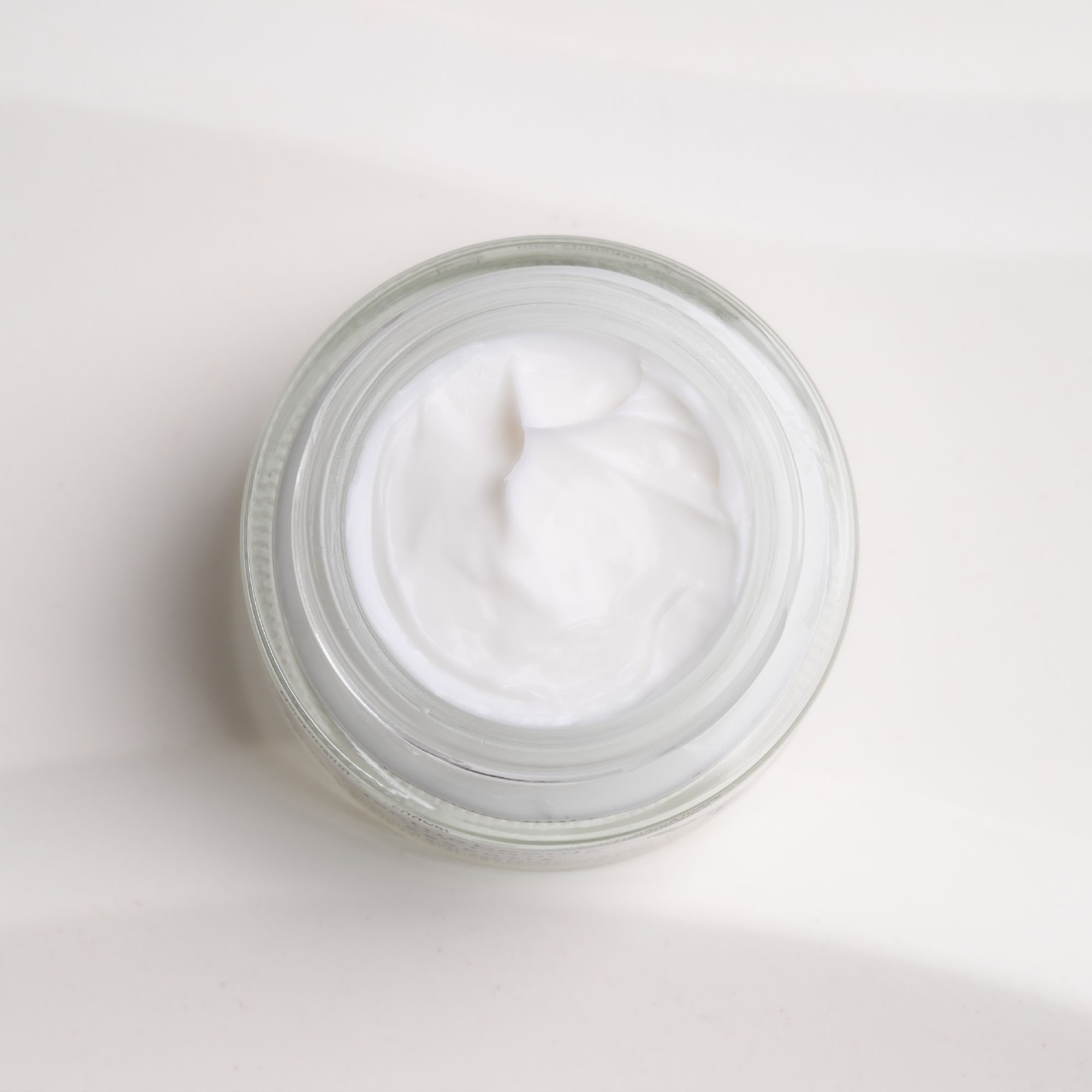 Glasbehälter mit weißer Creme. Draufsicht.