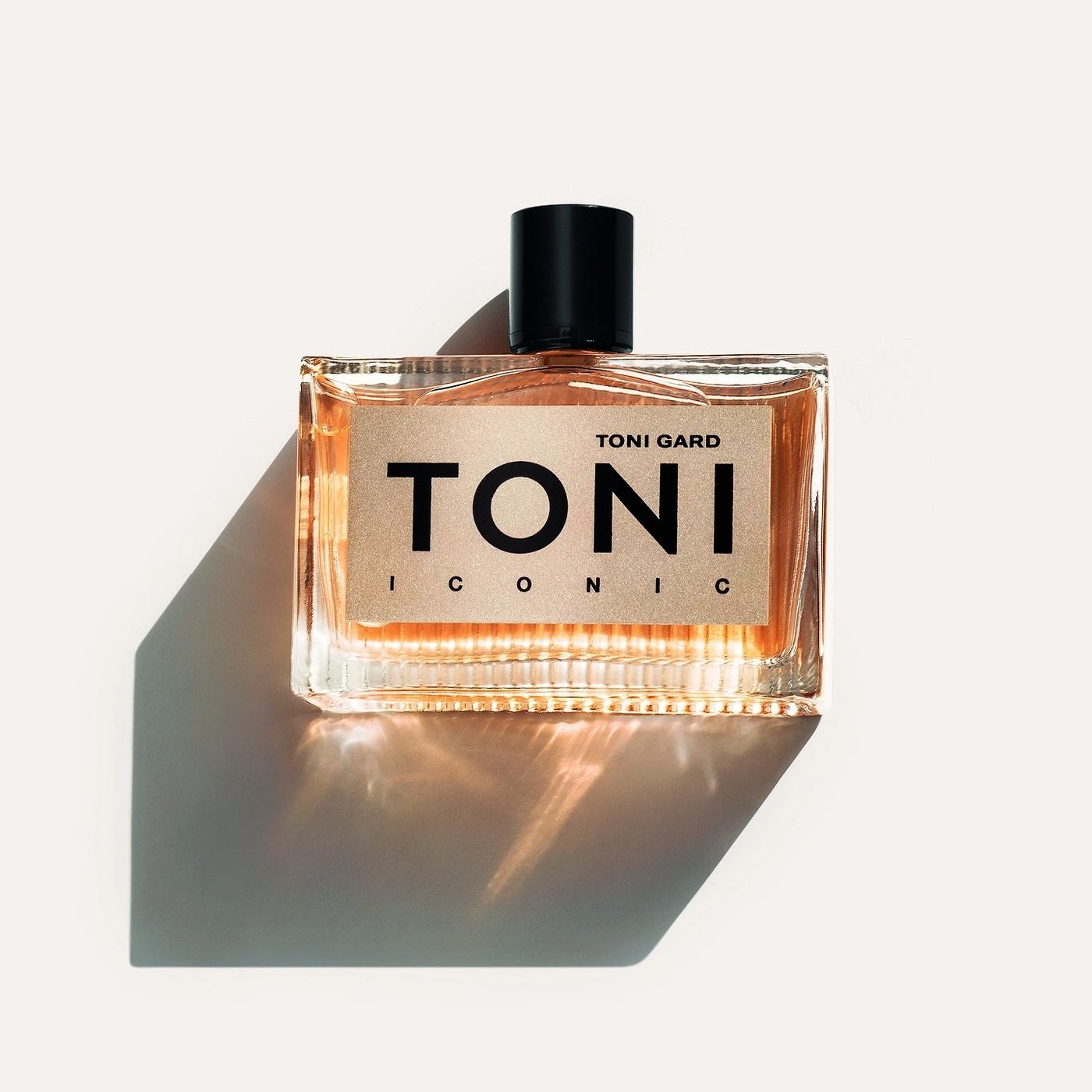 Rechteckige Glasflasche mit goldfarbenem Etikett. Schwarzer Schriftzug TONI ICONIC. Schwarzer Verschluss.