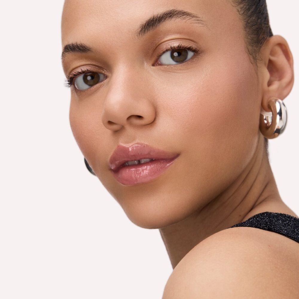 Porträt einer Frau mit glänzenden Lippen. Trägt Ohrringe.