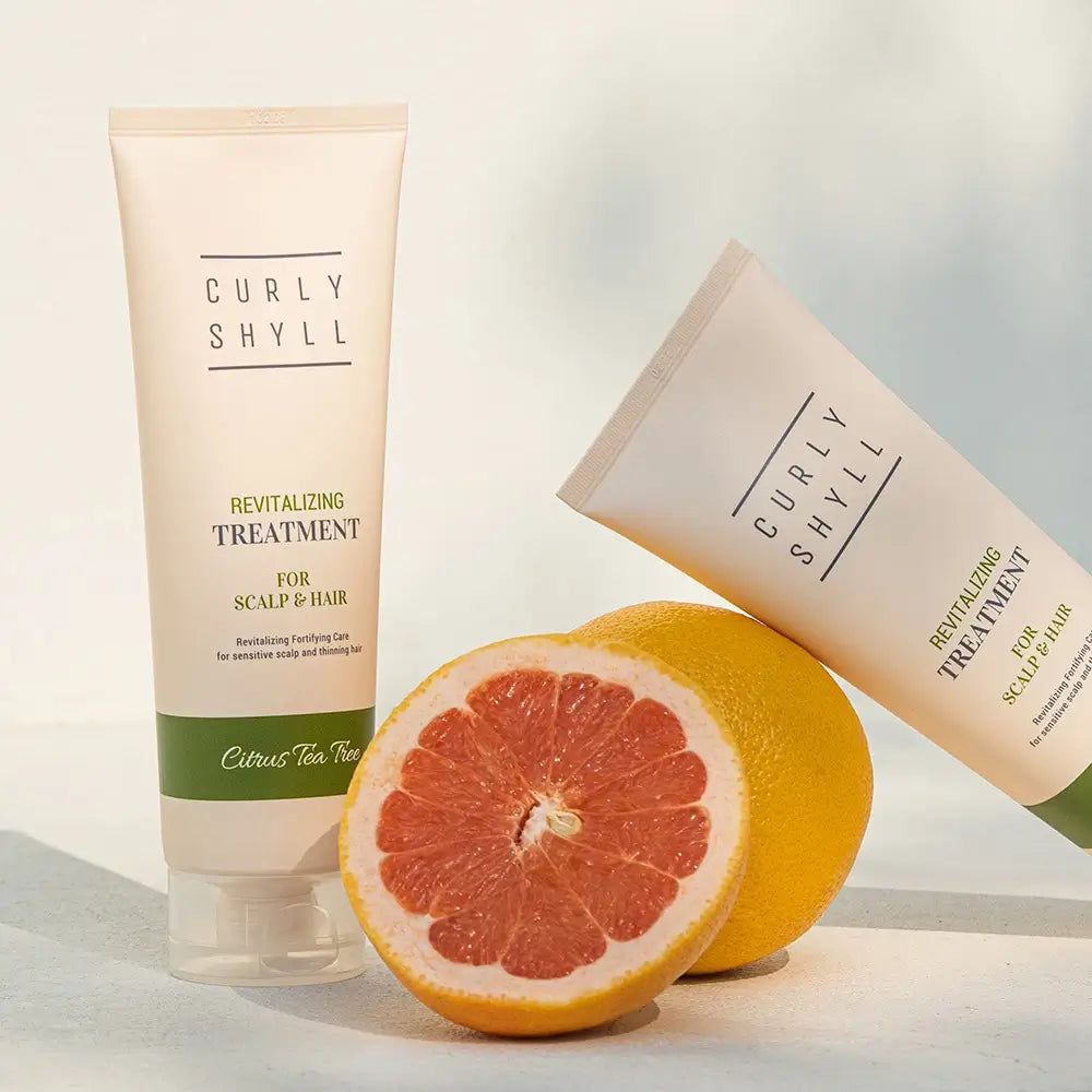 Zwei Tuben und eine Grapefruit. Text: CURLY SHYLL, Revitalizing Treatment for Scalp & Hair. Grüner Streifen.