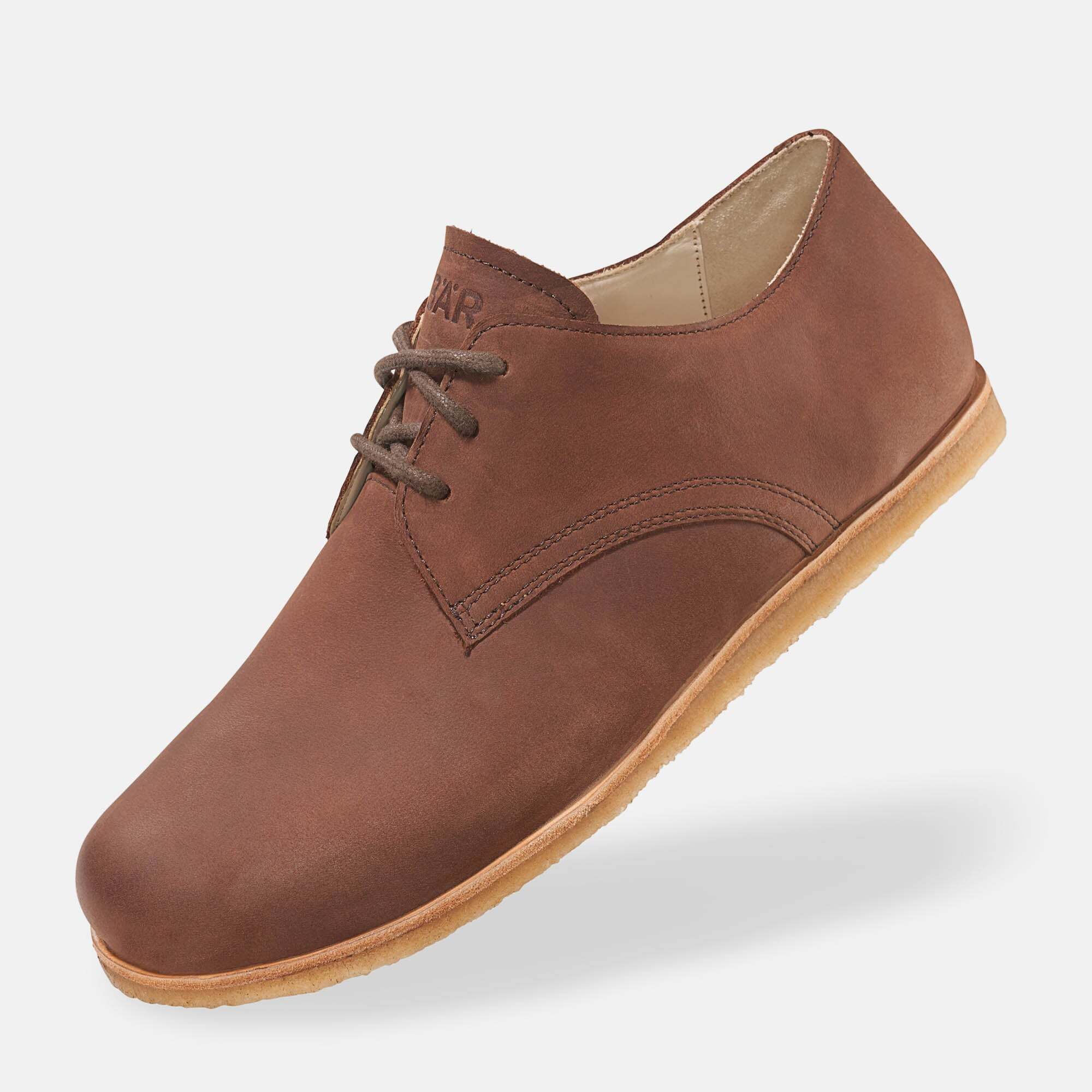 Brauner Lederschnürschuh. Hellbraune Sohle, Schnürsenkel. Logo auf der Zunge. Schuh leicht schräg gestellt.