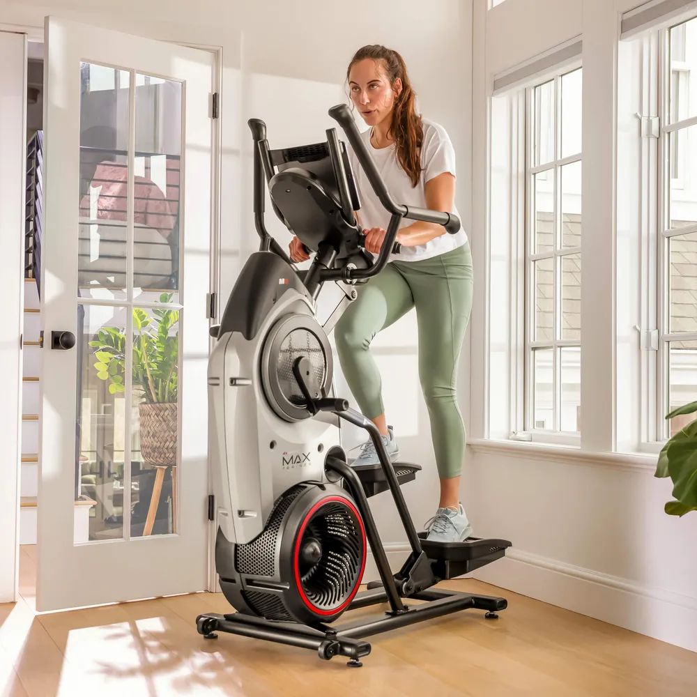 Femme s'entraînant sur un elliptique. Fenêtres en arrière-plan. MAX Trainer M6i.