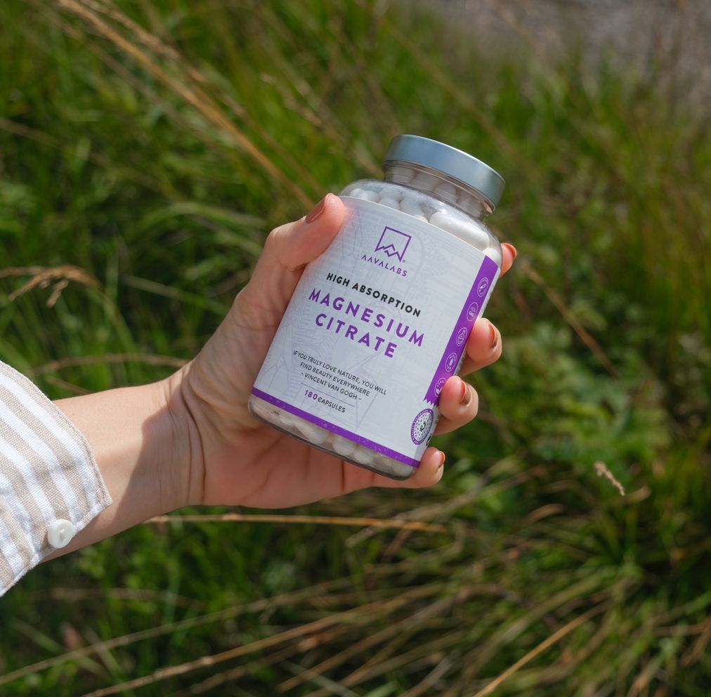 Eine Hand hält eine Flasche mit Magnesium Citrat Kapseln. Aufschrift: High Absorption Magnesium Citrate. 180 Kapseln.