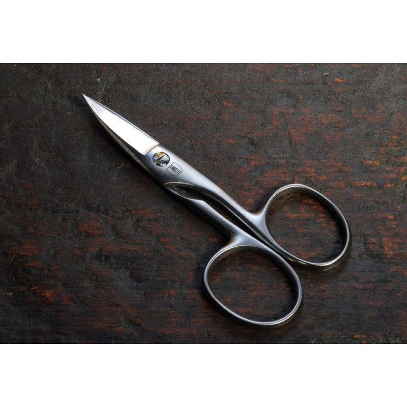 Nagelschere auf Holzuntergrund. Metall, matte Oberfläche. Ergonomische Griffe, spitz zulaufende Schneiden.