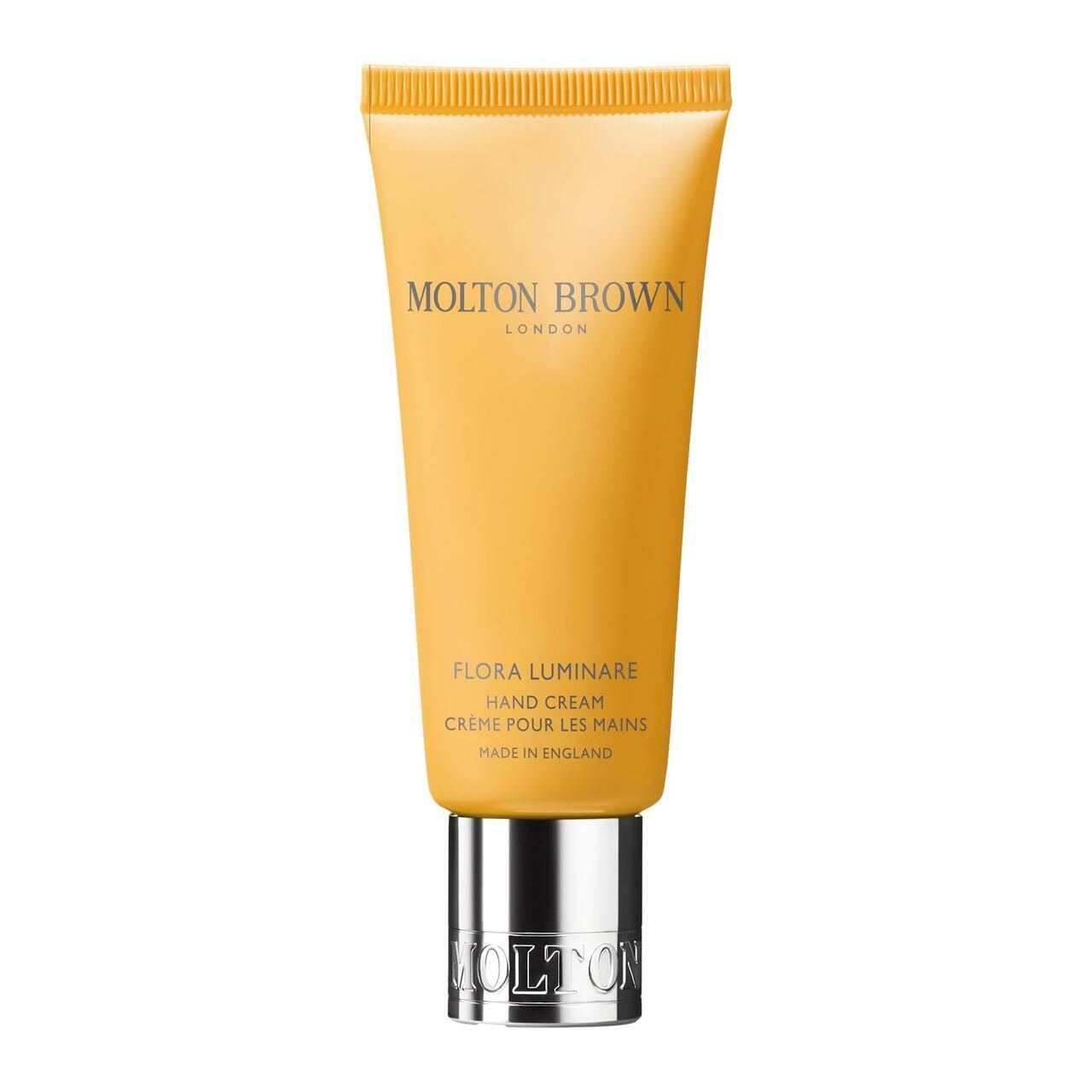 Gelbe Tube mit silbernem Verschluss. Aufschrift: Molton Brown, Flora Luminare Hand Cream. Hergestellt in England.