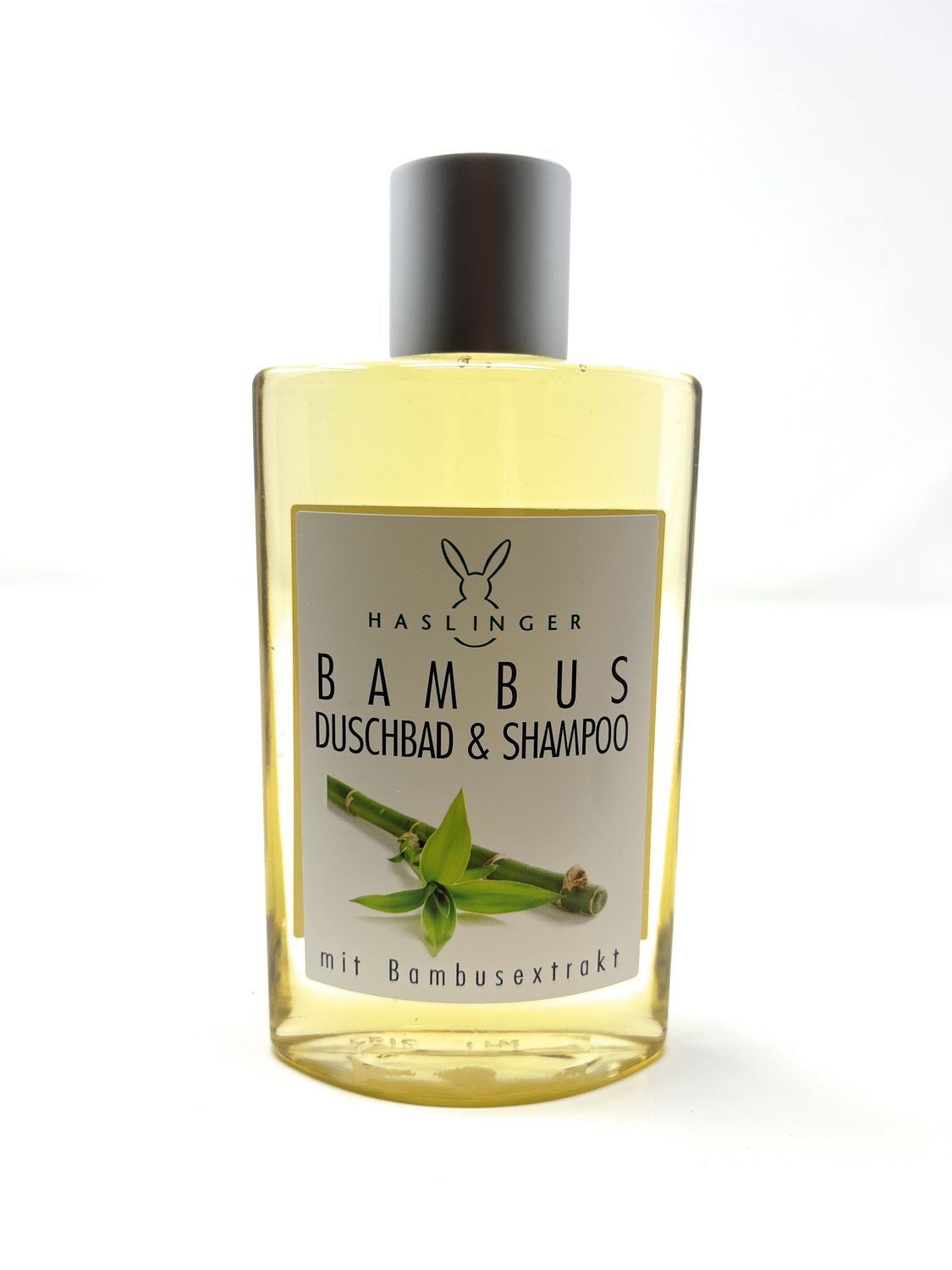 Haslinger Bambus Duschbad & Shampoo Flasche. Gelbe Flüssigkeit, grauer Deckel. Etikett mit Bambus-Illustration und Schriftzug.