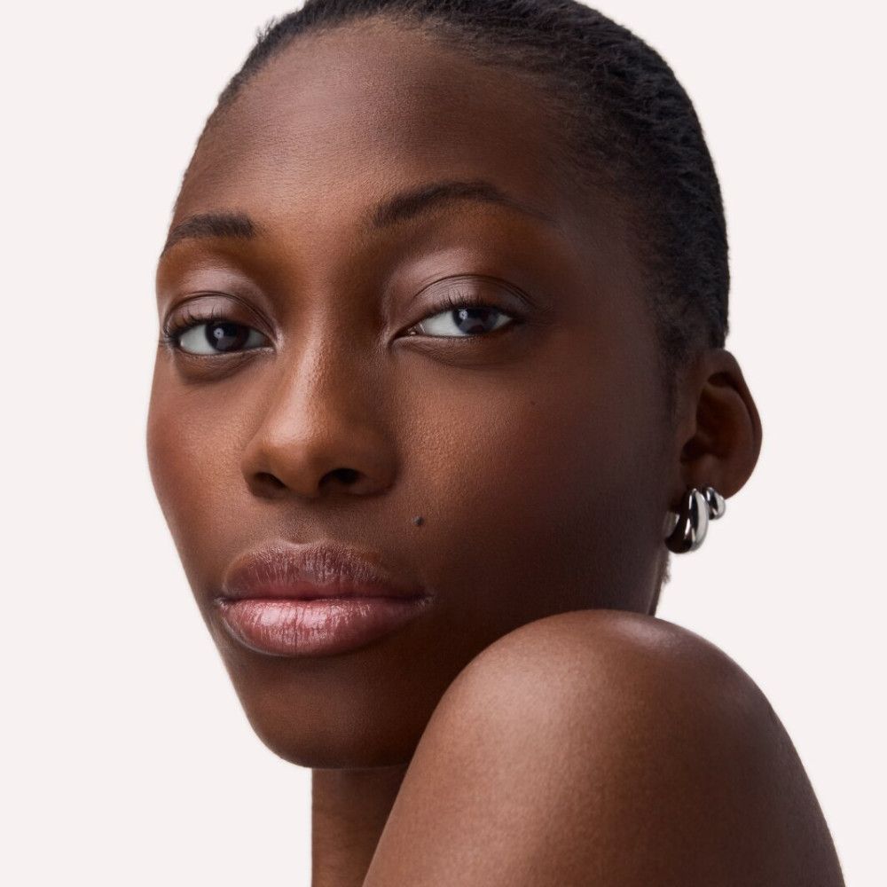 Porträt einer Frau mit glänzenden Lippen. Lippenbalsam-Effekt. Hautton: dunkel.