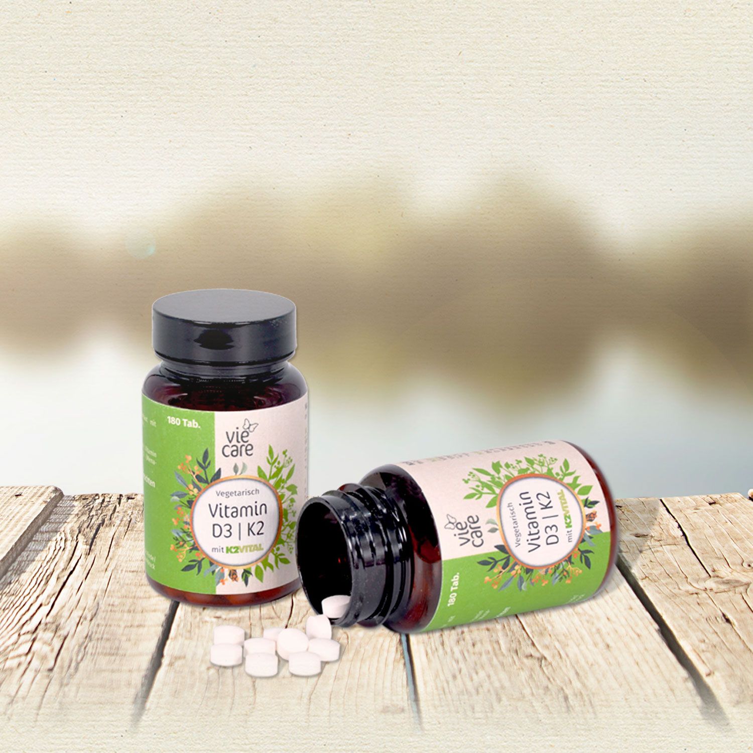 Zwei Flaschen, eine liegend, Tabletten daneben. Etikett mit 'viecare' und 'Vitamin D3 | K2'.