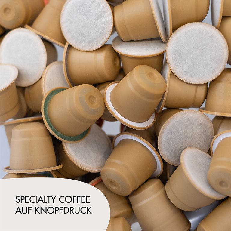 Haufen Kaffeekapseln. Aufdruck: Specialty Coffee auf Knopfdruck.