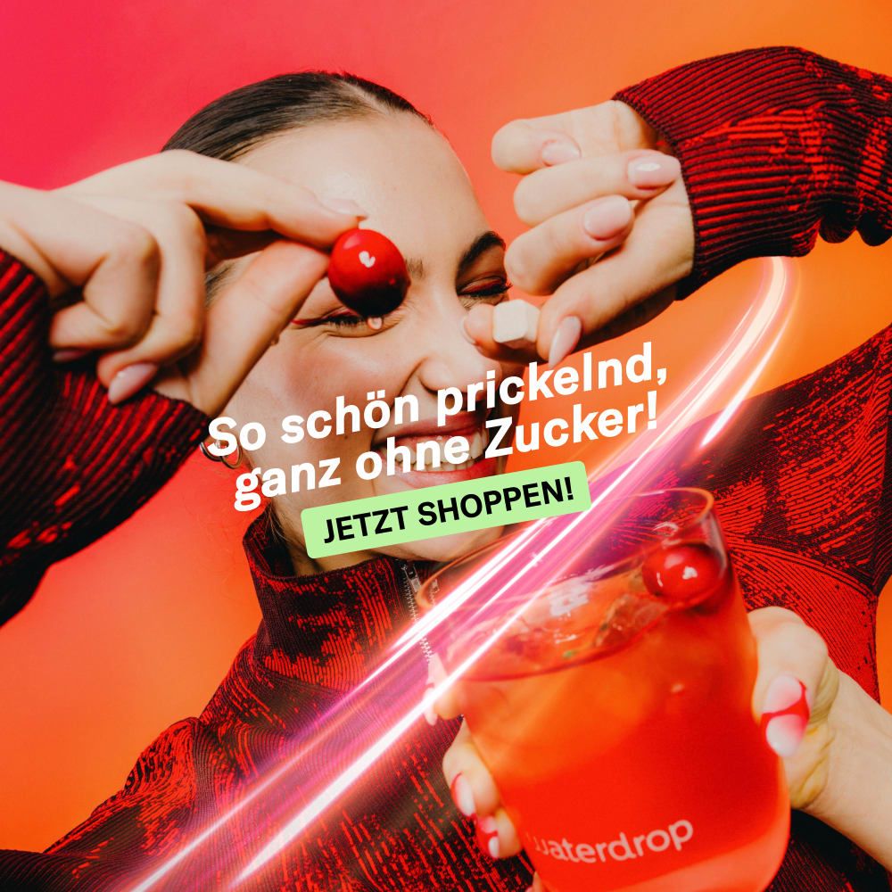 Frau hält Kirsche und Würfel. Glas mit Getränk. Aufdruck: waterdrop. Text: So schön prickelnd, ganz ohne Zucker! Jetzt shoppen!