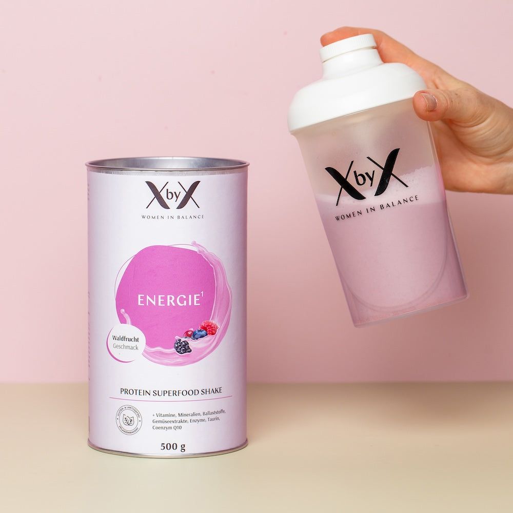 Dose mit „Energie“ und „Protein Superfood Shake“. Hand hält Shaker mit Shake. Dose und Shaker mit Logo.